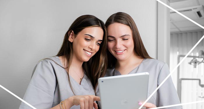 Zwei Nebeneinander stehende Mitarbeiterinnen der Zahnarztpraxis in Schwetzingen schauen auf ein Tablet